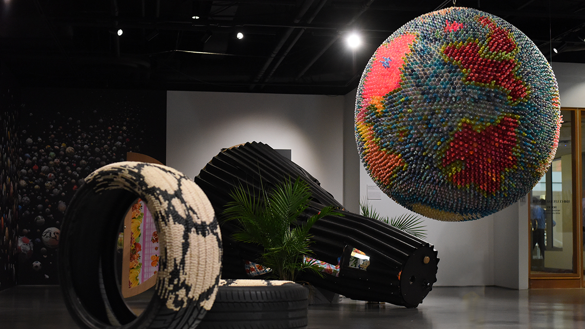 Another view of the exhibition Single-Use Planet, including a large planet made up of plastic baby bottles.